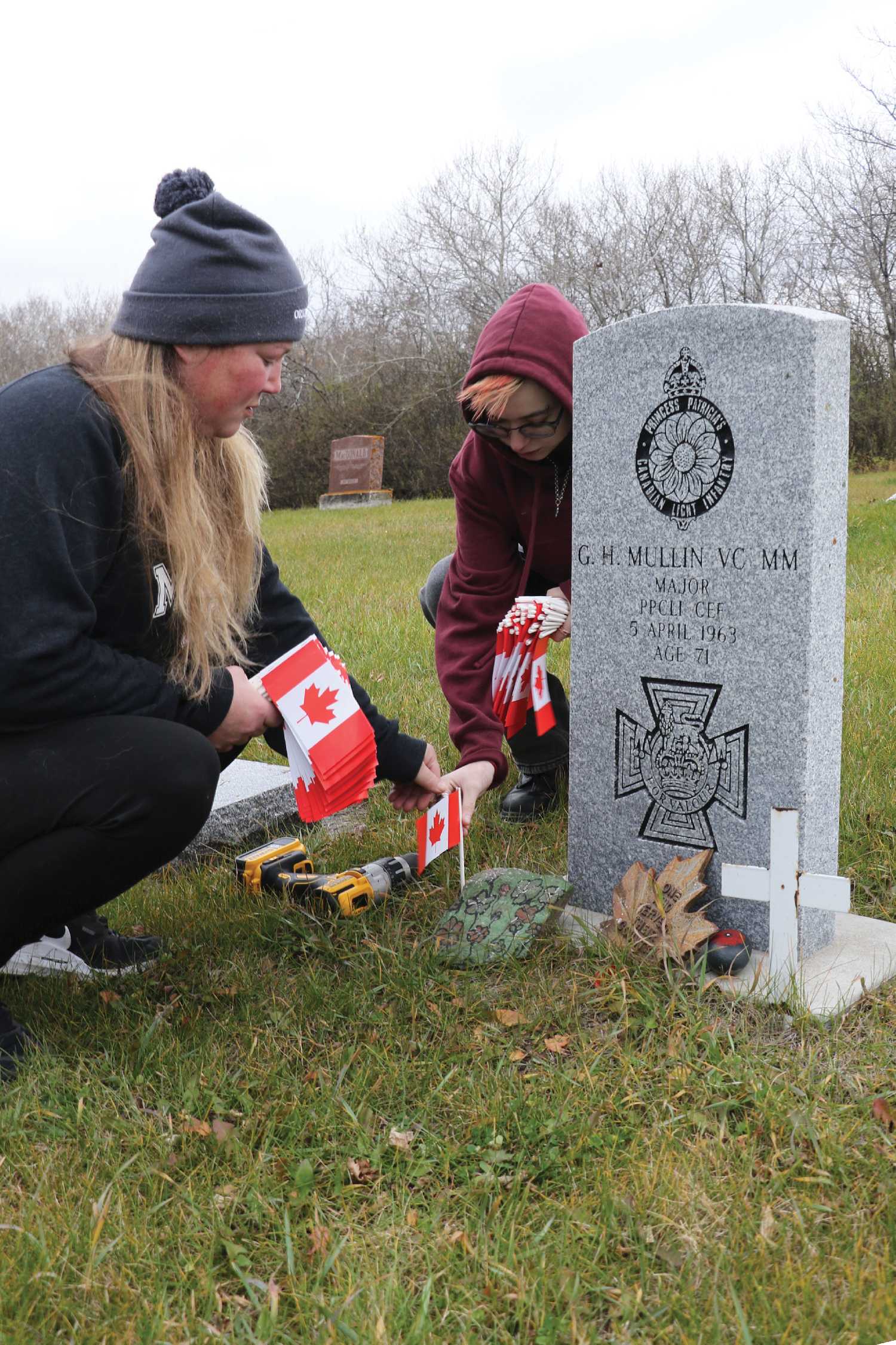 Shannon Beckett and Ella Beckett Dodsworth placing a flag on the gravestone of Victoria Cross winner Sergeant Harry Mullin.
